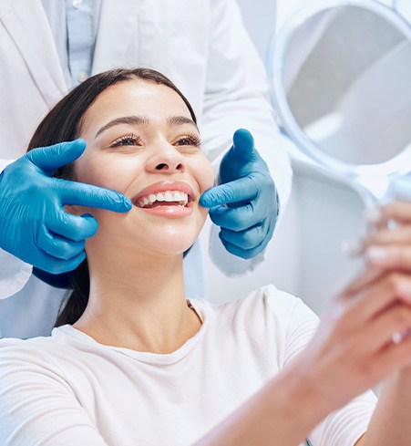 Patient smiling at reflection in handheld mirror
