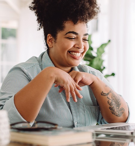 Woman smiling while working on laptop at home