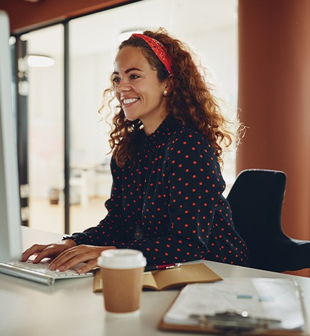 Woman smiling while working on computer in office