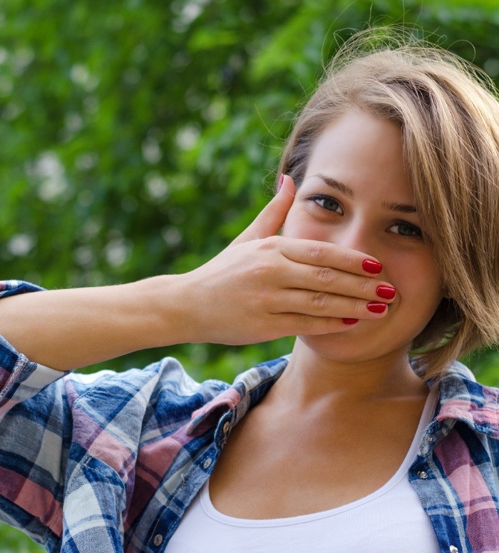 Woman experiencing orthodontic emergency covering her mouth