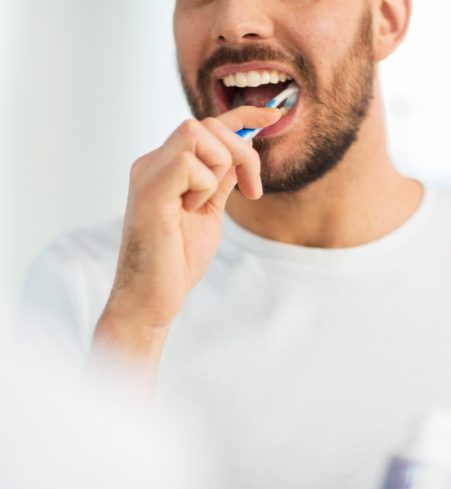 Person brushing teeth to avoid orthodontic emergencies