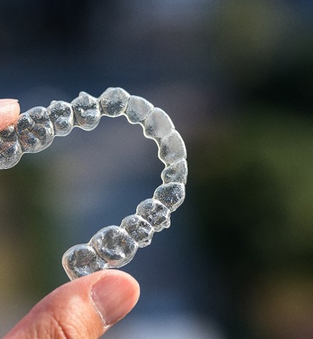 Closeup of patient holding Invisalign aligner