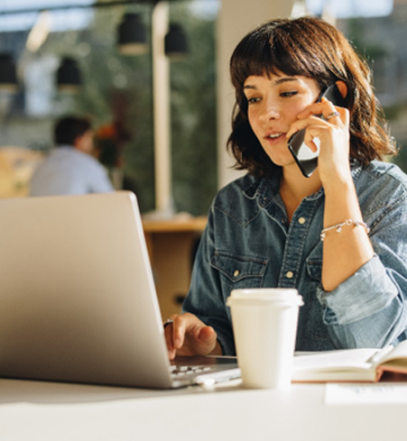 Woman talking on phone and looking at laptop
