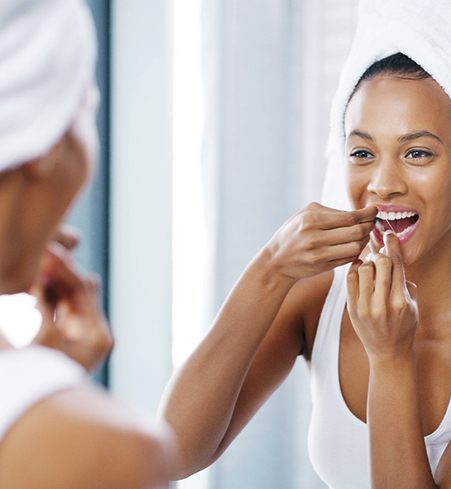 Closeup of woman flossing her teeth in bathroom