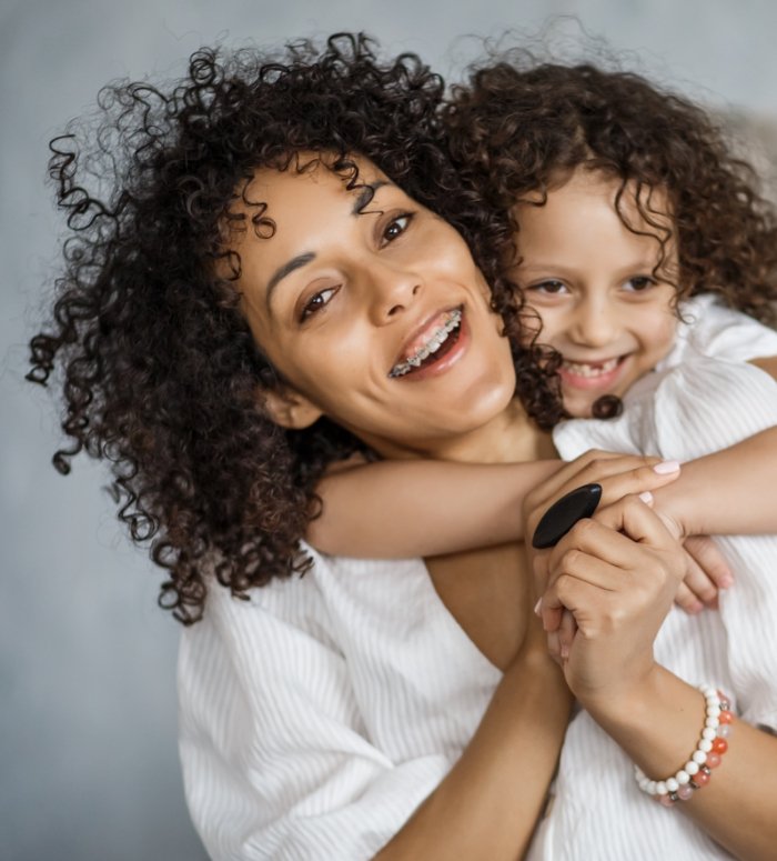 Woman receiving orthodontic services smiling with her child