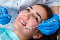 Patient in dental chair smiling after getting braces placed