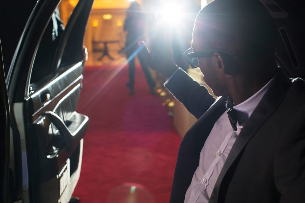 Man in tuxedo waving at crowd on red carpet