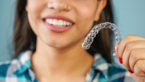 a patient smiling and holding their Invisalign aligner